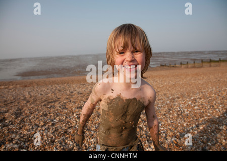 Kinder, die im Schlamm auf felsigen Strand bedeckt 