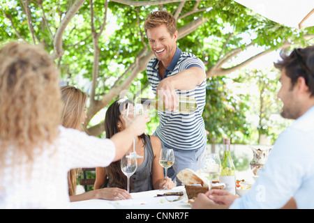 Man gießt Wein für Freunde am Tisch Stockfoto