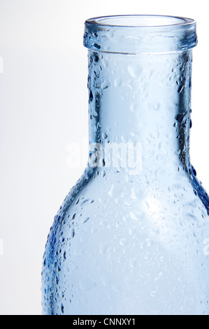 Vordergrund einer blauen Glasflasche mit Spritzer Wasser und weißem Hintergrund Stockfoto