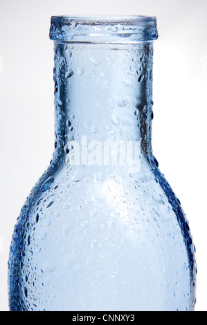Vordergrund einer blauen Glasflasche mit Spritzer Wasser und weißem Hintergrund Stockfoto