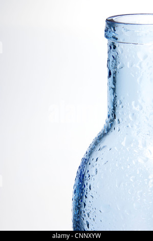Vordergrund einer blauen Glasflasche mit Spritzer Wasser und weißem Hintergrund Stockfoto