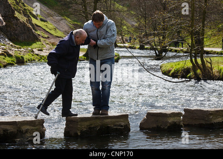 Alter Mann geholfen, über die Stepping Stones, Dovedale, Peak District National Park, Derbyshire Stockfoto