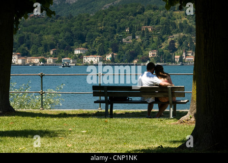 Ein Mann und eine Frau sitzen und kuscheln, Blick über den Comer See, Italien. Stockfoto