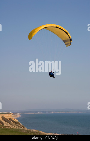 Para Segelflugzeug - schwebend über die Klippen und das Meer - gelbe Haube - blauer Himmel - Sonnenschein Stockfoto