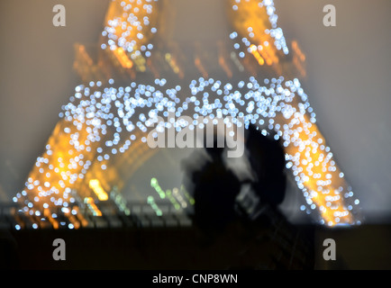 Romantische verschwommenes Bild von zwei Personen in der Nacht gegen Eiffelturm, Paris. Stockfoto