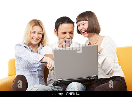Drei glückliche Erwachsene Jugendliche mit Laptop-Computer auf hellen gelben Sofa sitzen Stockfoto