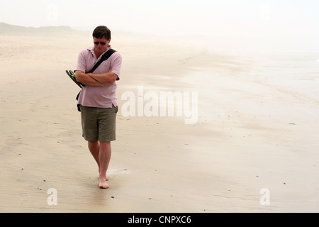 Einsamer Mann mittleren Alters zu Fuß am Strand Suche deprimiert. Stockfoto