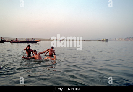 Drei junge indische Männer Baden und spielen im Ganges in der alten indischen Stadt Benares (Varanasi), Uttar Pradesh, Indien. Stockfoto
