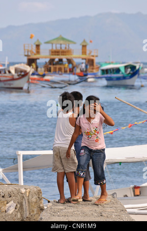 3 asiatische philippinische Kinder 2 Jungs suchen Schiffe 1 enttäuscht Mädchen zu Fuß vom Meer entfernt, Sabang Puerto Galera Asien Stockfoto