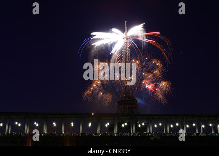 Parisern und Touristen beobachten Bastille Day Feuerwerk rund um den Eiffelturm mit Passy Brücke im Vordergrund in Paris, Frankreich. Stockfoto