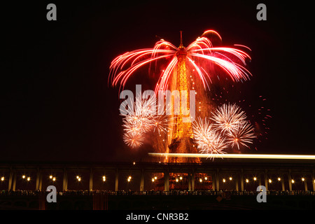 Parisern und Touristen beobachten Bastille Day Feuerwerk rund um den Eiffelturm mit Passy Brücke im Vordergrund in Paris, Frankreich. Stockfoto