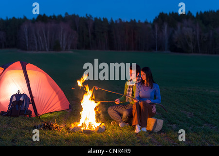 Camping Nacht paar kochen durch Lagerfeuer Rucksack in romantische Landschaft Stockfoto