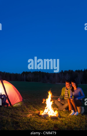 Camping Nacht paar kochen durch Lagerfeuer Rucksack in romantische Landschaft Stockfoto