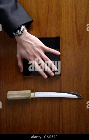 Des Mannes Hand, quadratische Platte und Messer Stockfoto