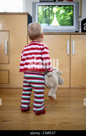 Baby Girl Holding Teddybär und man Fernsehen, London, England Stockfoto