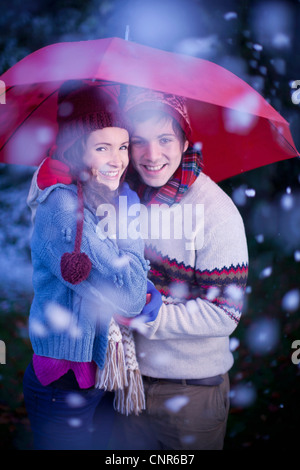 Lächelnde paar unter Dach im Schnee Stockfoto