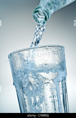 Nahaufnahme von Mineralwasser, das in ein Glas gegossen wird. Stockfoto
