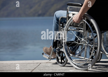 Mann im Rollstuhl sitzend durch Wasser Stockfoto