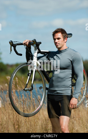 Mann mit dem Fahrrad auf der Schulter in der Natur, Porträt Stockfoto