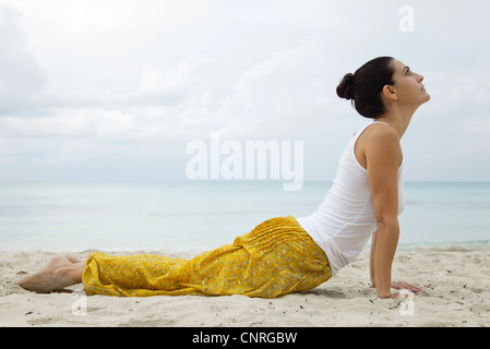 Reife Frau in Kobra-Pose am Strand, Seitenansicht Stockfoto