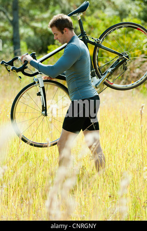 Mann mit Fahrrad auf der Schulter, ein Spaziergang durch Rasen Stockfoto