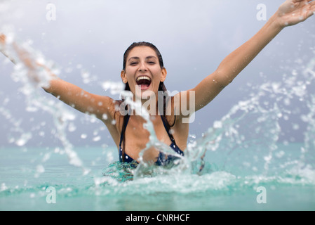 Junge Frau Spritzwasser und lachen Stockfoto