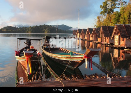 Longtail-Boote und Hütten am Cheow Lan See im Morgenlicht, Thailand, Phuket, Khao Sok NP Stockfoto