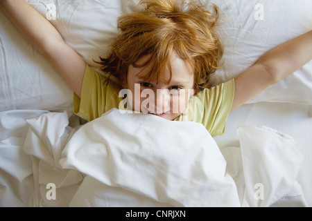 Junge im Bett liegend, mit ausgestreckten Armen Stockfoto