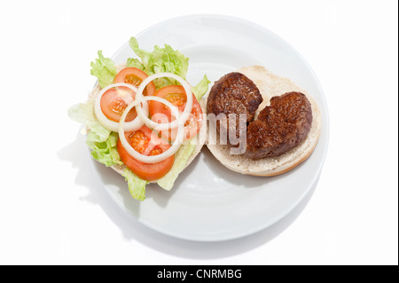 Ein gebrochenes Herz geformt Beef-Burger auf einem Brötchen mit Tomatensauce und einem Beilagensalat Stockfoto