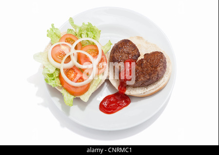 Ein gebrochenes Herz geformt Beef-Burger auf einem Brötchen mit Salat und Tomate Soße Nässen aus es Stockfoto