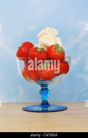 Erdbeeren und Cornish Clotted Cream in einem Eisbecher Glas auf eine Holzoberfläche vor blauem Himmel Stockfoto