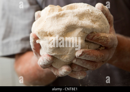 Hände des Mannes hält frischen Brotteig Stockfoto