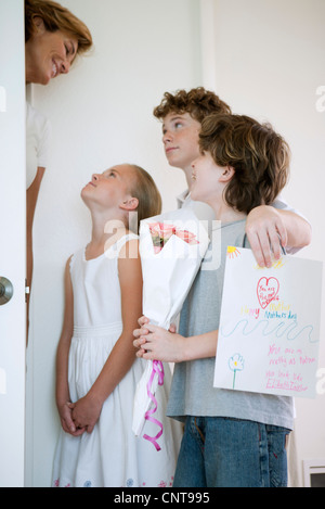 Kinder geben Mutter Blumen und handgemachte Grußkarte Stockfoto