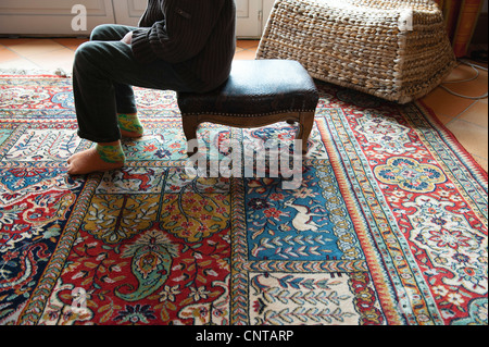 Frau sitzt auf Ottomane im Wohnzimmer, niedrige Abschnitt Stockfoto