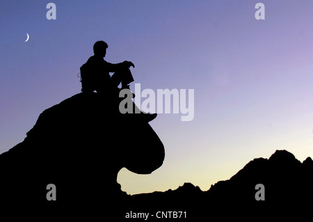 Silhouette von einem Berg Wanderer sitzen auf einem bizarr geformten Felsen bei Sonnenuntergang Enjoing die Ansicht, Frankreich, Alpen Stockfoto