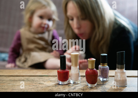 Flaschen Nagellack, Mutter bläst auf junge Tochter Zehen im Hintergrund Stockfoto