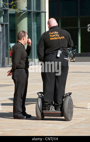 Zwei Wachleute, einer auf einem Segway, bei MediaCityUK, Salford Quays, Manchester, England, UK Stockfoto