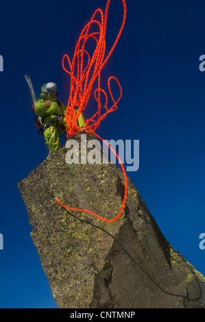 Ski-Alpinisten auf einem Felsen steht, warf ein rotes Klettertau, Frankreich, Alpen Stockfoto