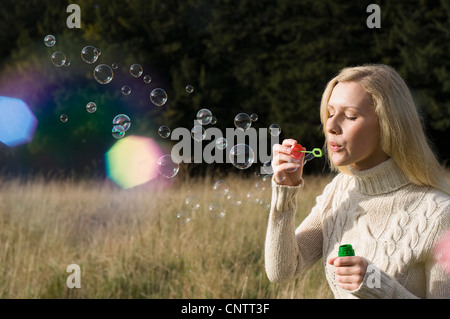 Frau bläst Luftblasen im Weizenfeld Stockfoto