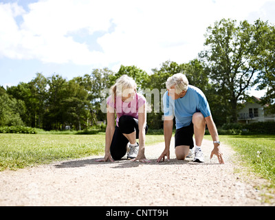 Älteres Ehepaar kauerte in Startposition Stockfoto