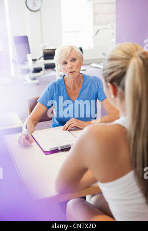 Trainer im Gespräch mit Frau im Fitness-Studio Stockfoto