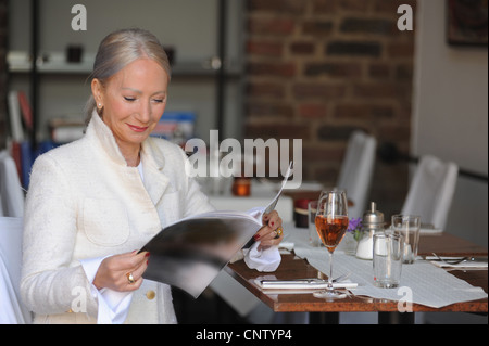 Ältere Frau liest Magazin im café Stockfoto