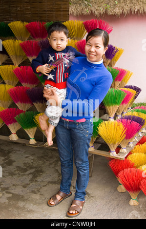 Vertikale Porträt einer jungen vietnamesischen Frau mit ihrem kleinen Sohn neben bunten Sticks verwendet, um Weihrauch oder Räucherstäbchen Stockfoto