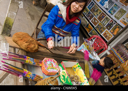 Horizontale Ansicht einer jungen vietnamesischen Frau machen Weihrauch oder Räucherstäbchen an ihrem Marktstand. Stockfoto