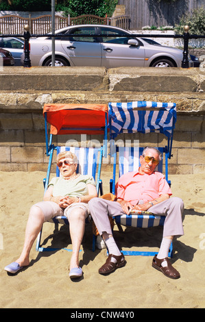 Großbritannien, England, Hampshire, Isle of Wight, Sandown, älteres Ehepaar schlafen in Liegestühlen am Strand von Sandown Stockfoto