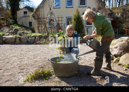 Brennnessel (Urtica Dioica), Frau mit ihrer Tochter, die Herstellung von Brennnessel Gülle aus frischen Brennnesseln für ökologische Schädlingsbekämpfung und Dünger, Deutschland Stockfoto