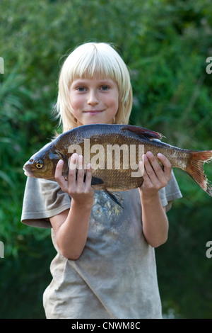 Brachsen, Süßwasser Brassen, Karpfen Brassen (Abramis Brama), junge stolz präsentieren einen gefangenen Fisch Stockfoto