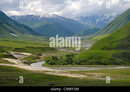 Blick über das weite Tal mit dem Fluss vor Bergpanorama, verlassene Dorf und mittelalterliche Festung in der Ferne, Georgia, Truso-Tal Stockfoto