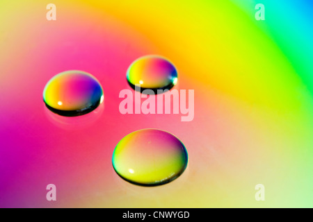 Ein Makro Nahaufnahme Schuss von drei Wassertropfen auf einem Regenbogen farbige Hintergrund Stockfoto
