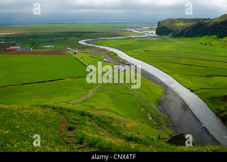 Blick von einer Anhöhe auf eine weite Ebene mit Fluss Skoga Wicklung durch es und die kleine Stadt Skogar auf der linken Seite, Island, Skogar Stockfoto